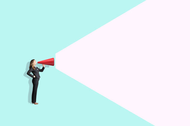 A woman shouts into a megaphone isolated against a green background.