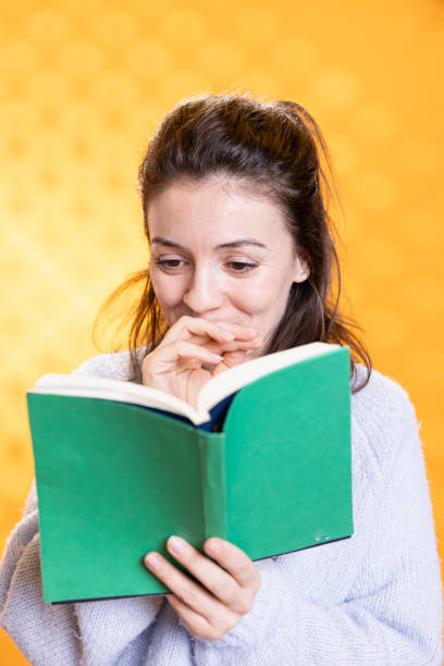 istock Amused woman browsing through funny book pages, laughing, studio background 2157869344