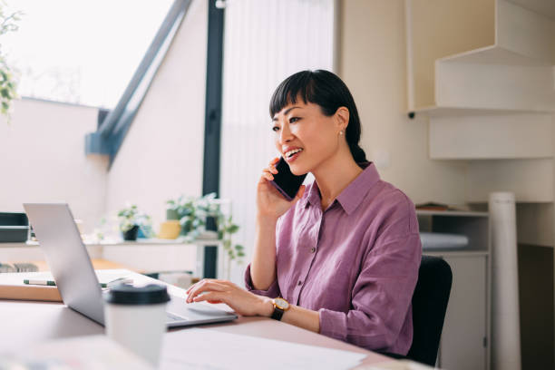 istock Businesswoman Working On Laptop While Talking On Phone 2157872722