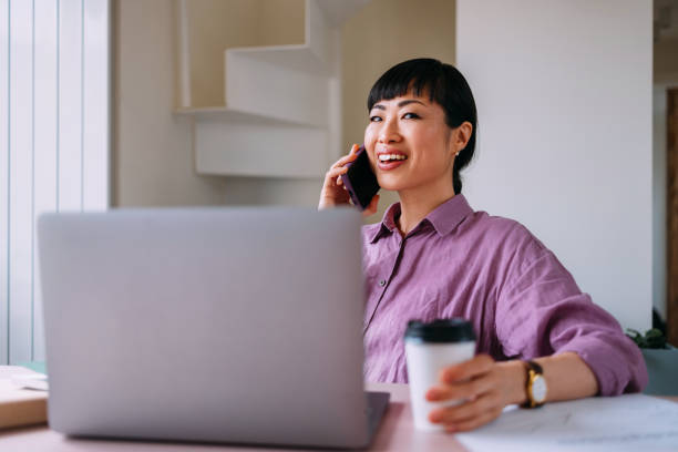 istock Smiling Woman Working Remotely On Laptop While On Phone Call 2157872743