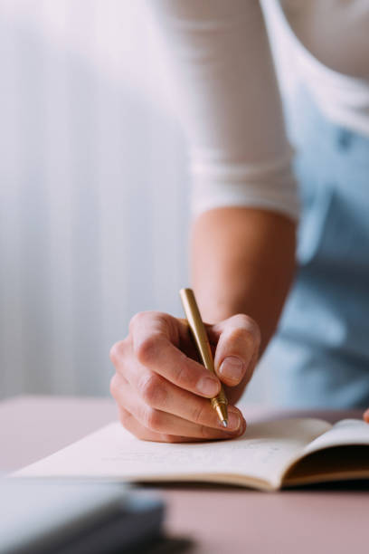 Close-up view of a person writing in a notebook with a pen. Ideal for educational, business, or note-taking context.