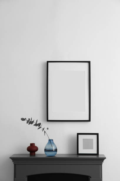 istock Fireplace, decorative elements and photo frames in room with white wall. Interior design 2157876062