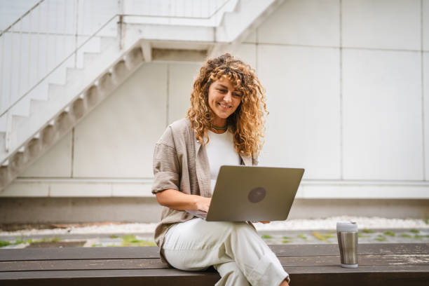 istock Adult woman sit on a bench use laptop while she have a break at work 2157877996