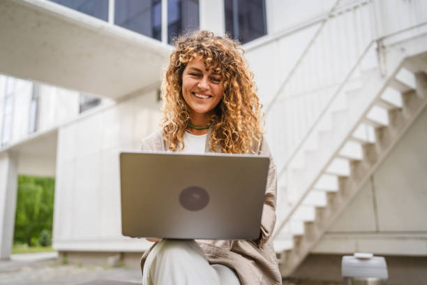 istock Adult woman sit on a bench use laptop while she have a break at work 2157878230