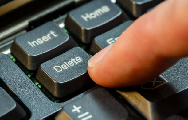 Finger pressing the Delete key on a simple laptop computer keyboard, object macro detail, extreme closeup. Deleting files, removing content, digital data deletion abstract concept symbol, one person pulsando con el dedo la tecla suprimir en el teclado de un simple ordenador portátil, detalle macro del objeto, primer plano extremo. eliminación de archivos, eliminación de contenido, eliminación de datos digitales, símbolo de concepto abstracto, una