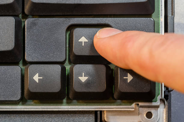 istock Man pressing the up arrow key on a simple laptop computer keyboard, top down table top view from above. Finger presses the forward arrow, moving forwards, progress simple abstract concept, one person 2157883114