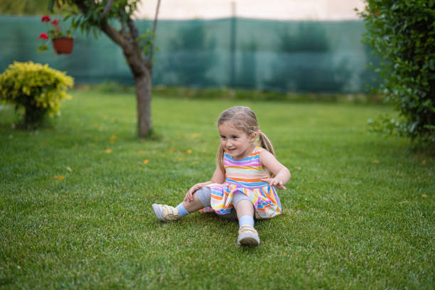 Cute little girl jumping for fun, playing in the garden in a green grass backyard.