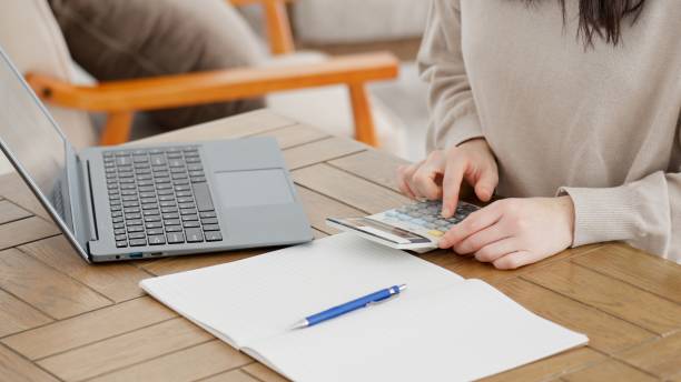 istock A woman calculating expenses with a calculator 2157888718