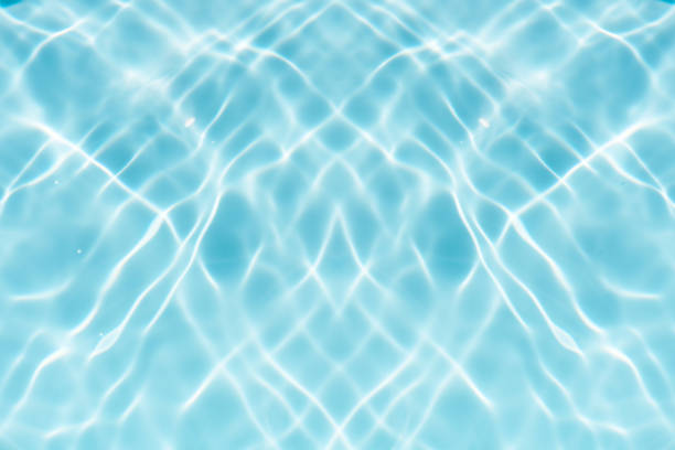 Blue water with ripples on the surface. Defocus blurred transparent blue colored clear calm water surface texture with splashes and bubbles. Water waves with shining pattern texture background.