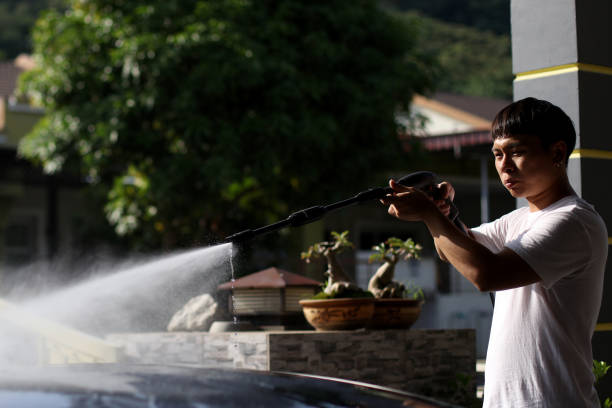 An Asian man is washing car at home