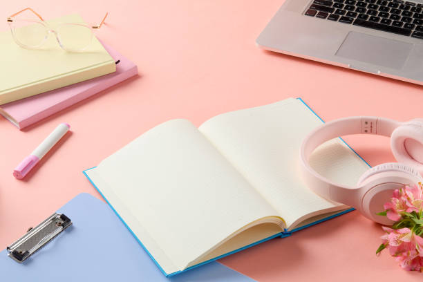istock White paper notebook with blue cover opened and featured on pink table top, decorated around with other stationary has pastel color. Photo was taken from above, empty space for product displaying 2157897818