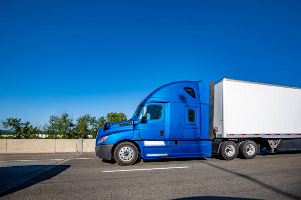Industrial carrier blue big rig semi truck tractor with extended cab for truck driver rest transporting cargo in dry van semi trailer running on the multiline highway road at sunny day