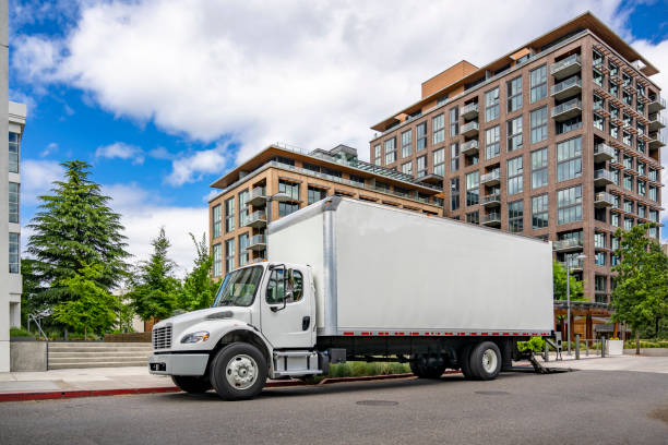 istock Compact powerful bonnet day cab middle duty rig semi truck carry goods in box tailer making delivery to customer in multilevel apartment 2157899506