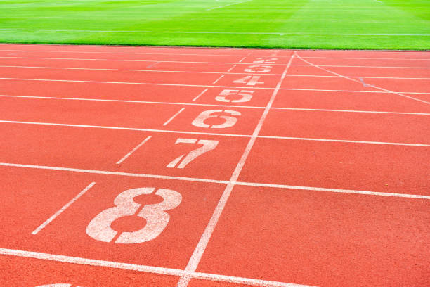 istock Red running track with green grass in stadium. Athletic competitions starting line positions from one to nine. 2157901022