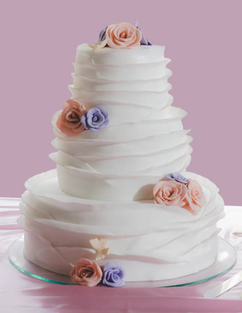 istock DELICIOUS THREE-TIER WHITE WEDDING CAKE WITH ORANGE AND VIOLET FLOWER DETAILS 2157901191