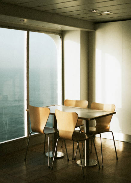 Empty table and chairs by a window on a ferry at sea