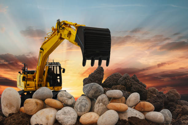 Excavators are digging the soil and stone in the construction site on the sunset background