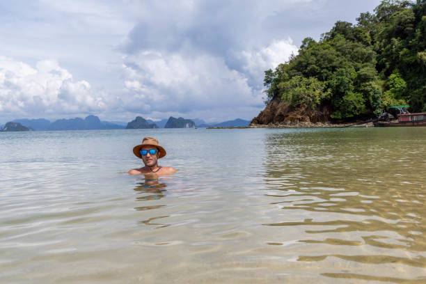 istock Man Relaxing in Shallow Sea Near Lush Greenery 2157906646