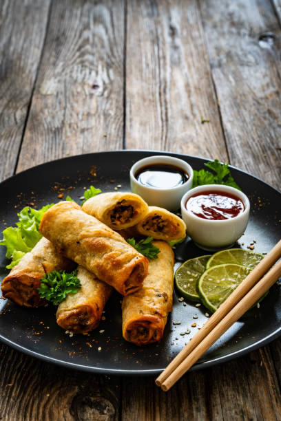 istock Spring rolls filled with meat and vegetables served with soy sauce on wooden table 2157906747