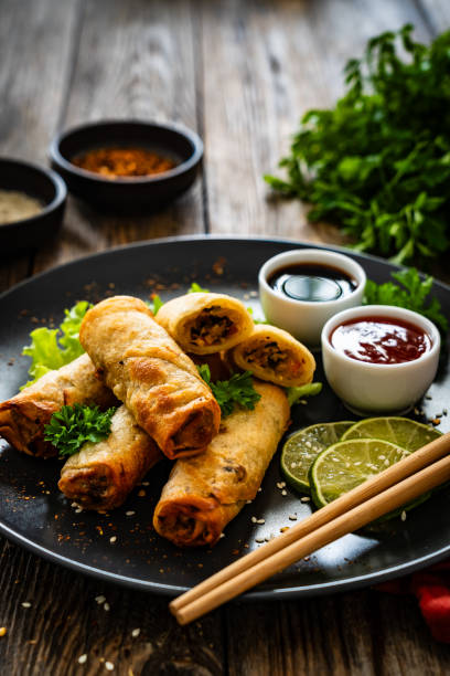 istock Spring rolls filled with meat and vegetables served with soy sauce on wooden table 2157906758