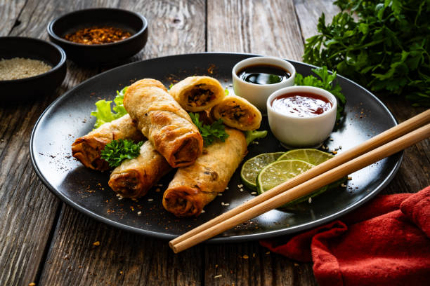 istock Spring rolls filled with meat and vegetables served with soy sauce on wooden table 2157906779