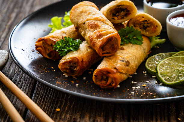 istock Spring rolls filled with meat and vegetables served with soy sauce on wooden table 2157906805