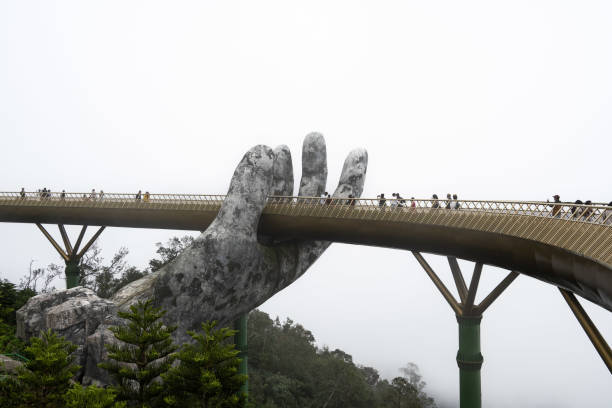 Experience the breathtaking Golden Bridge in Da Nang, Vietnam, where people stroll along the iconic structure held by giant hands. This stunning landmark offers panoramic views and a unique architectural marvel.