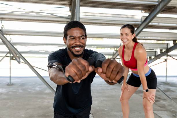 Man using a cable machine next to his fitness trainer
