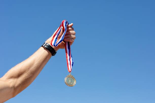 istock Man holding a gold medal after winning a race 2157912331