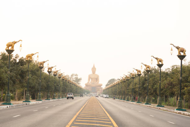 Highway road with sky clouds at sunset, The road leading to Phikun Thong Temple at Sing Buri, Thailand.