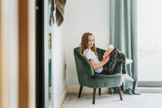 istock Girl reading a book on a couch, new normal hobby 2157914665