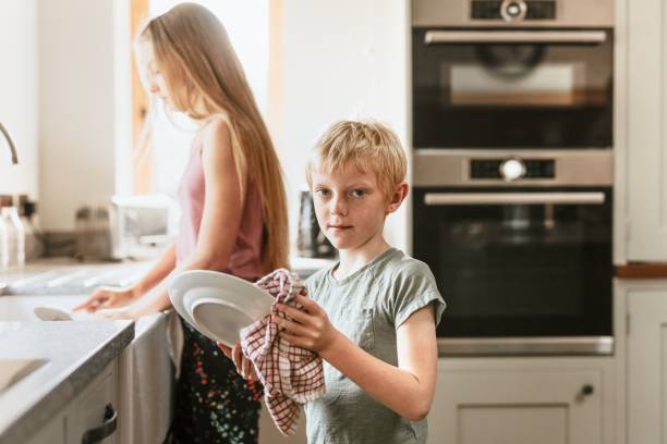 istock Young boy wiping dishes in kitchen, basic house chores 2157915024