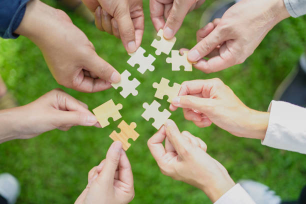 istock group leaders collaborate on green partnership, fitting together the pieces of environmental, social, and governance (ESG) strategies for sustainable success, symbolized jigsaw puzzle in hand. 2157919029