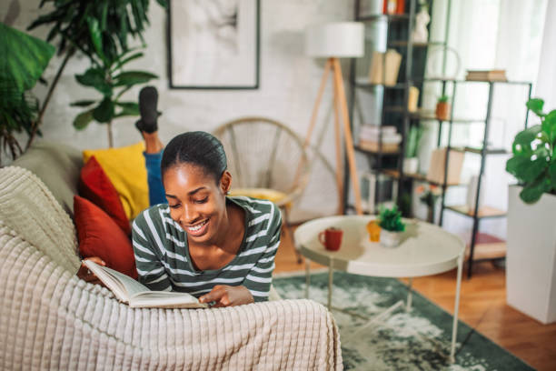 istock Young black woman reading a book at home 2157920587