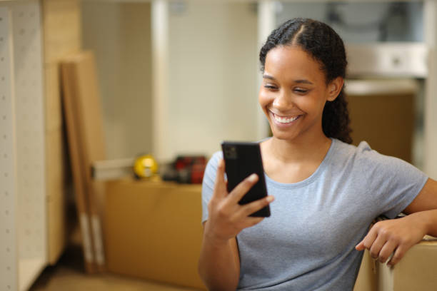 istock Happy black woman moving home checking phone 2157920589