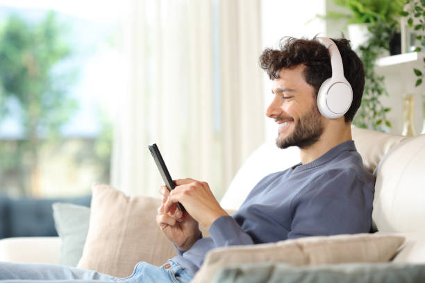 istock Happy man searching audio content on phone at home 2157921102