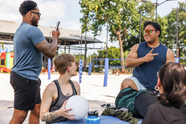 istock Weekend park volleyball gathering. Diverse friends engage in cheerful conversation, sharing a light moment under the sun 2157923074