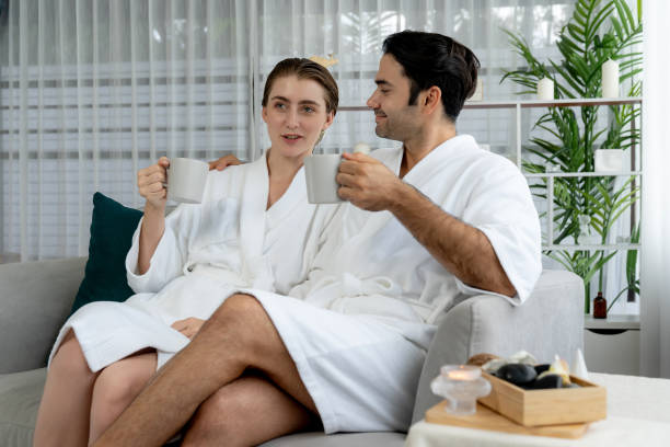 istock Couple wearing bathrobe relaxing with drinks in luxurious hotel spa. Quiescent 2157923870