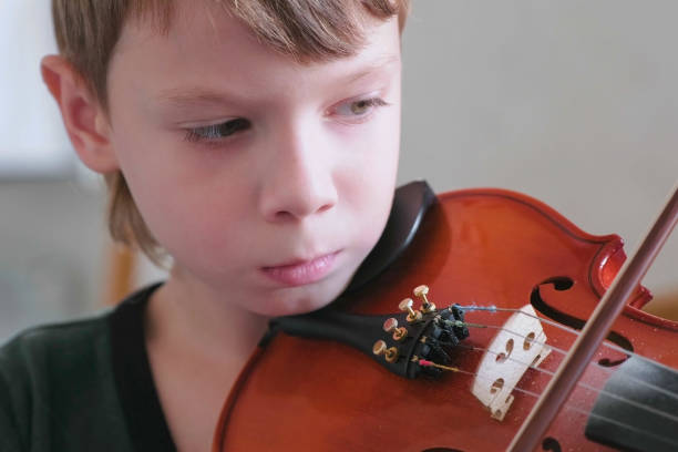istock Boy of 8 years is playing violin using notes. Face cloe-up. 2157924823