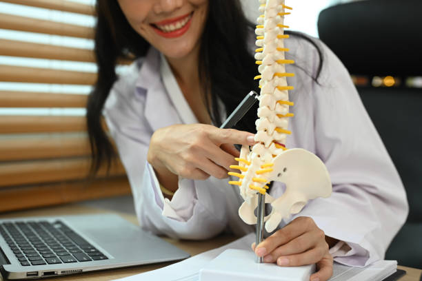 istock Physiotherapist showing a lumbar disc herniation with a spinal model while giving consultation at rehab clinic 2157926390