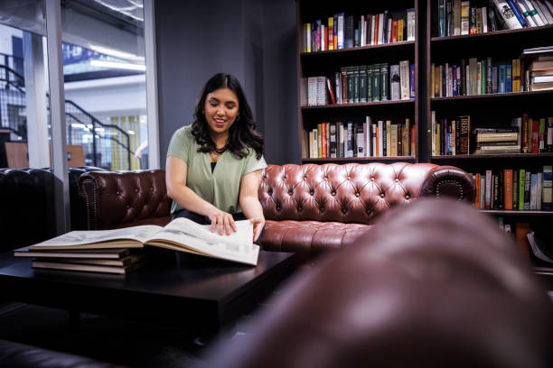 istock Engrossed in knowledge. Young Hispanic woman reading in cozy library setting. 2157929493
