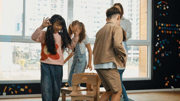 istock Diverse children playing musical chairs while teacher turn off music. Erudition. 2157929858