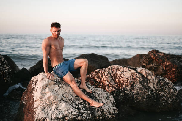 istock Man standing on boulders on shoreline 2157930698