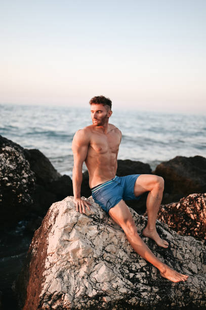 istock muscular young man on rock. 2157930699