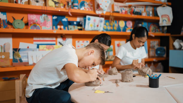istock Teenager using carving tool working at clay at pottery workshop. Edification. 2157931042