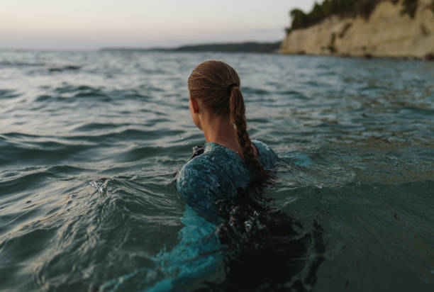istock Young woman is getting into the sea water 2157931500
