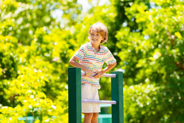 Child on playground. Active kid exercising in school yard. Children play and climb. Little boy on monkey bars. Kids having fun on sunny summer day in beautiful park.