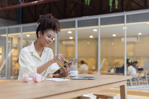 istock African American woman freelancer using tablet and working on laptop in office desk. 2157932259