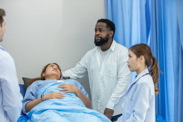istock Doctor Visiting  Patient On Ward. Hospitalized man lying in bed while doctor checking his. physician examining patient in hospital room. Hospital Ward 2157933286