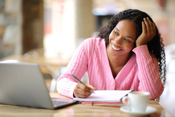 istock Happy black woman e-learning using laptop in a bar 2157933806